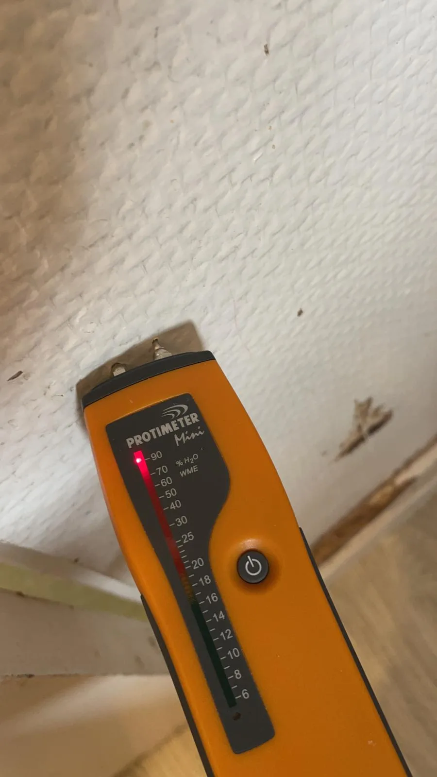 Humidimètre appliqué contre un plafond touché par un dégât des eaux